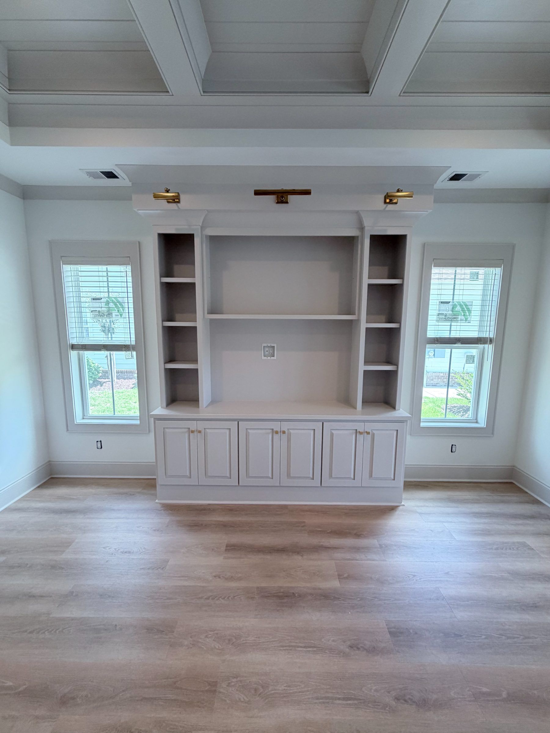 Faux wood blinds on custom color trim next to a bookcase