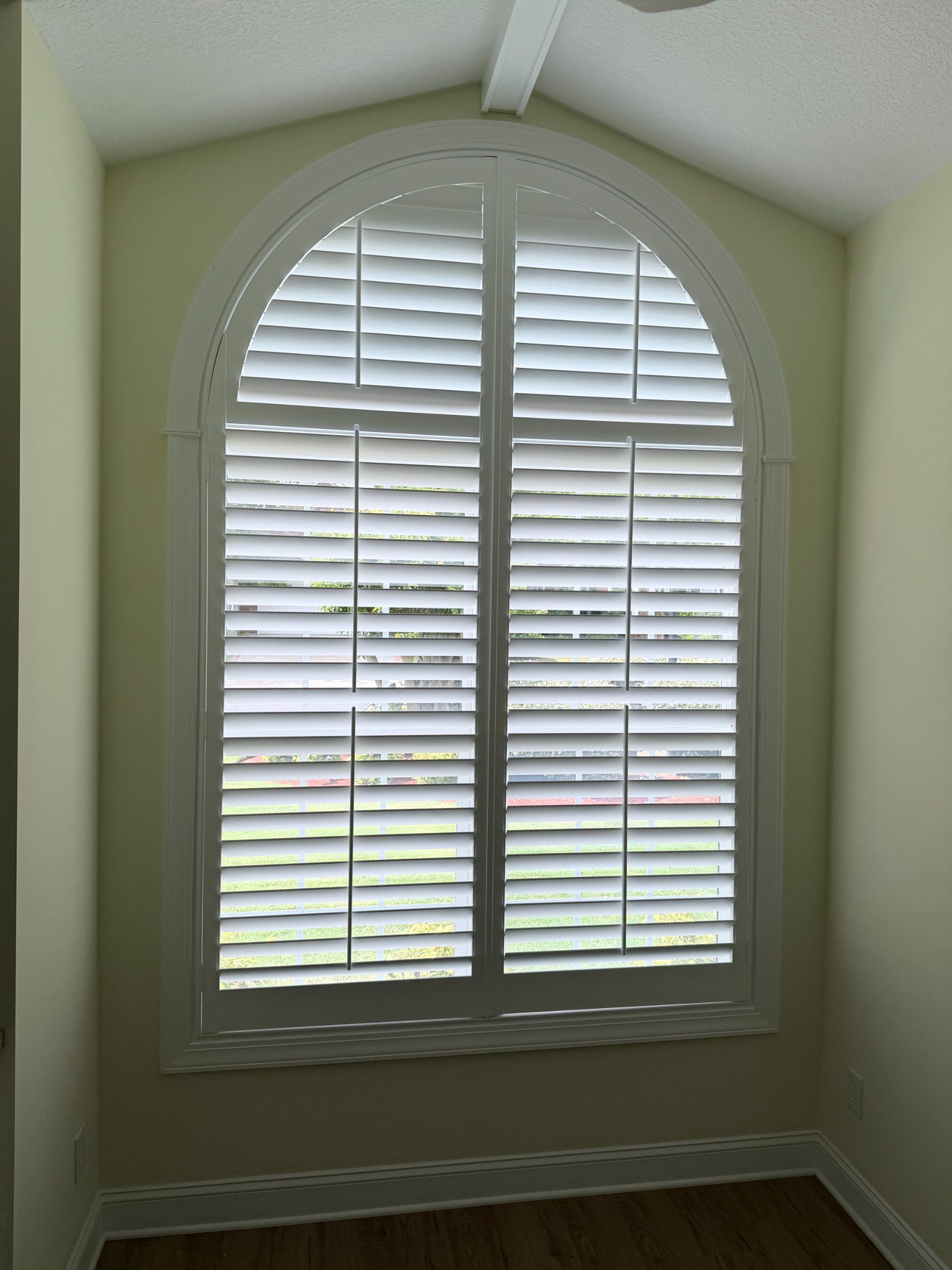 Center Open Arch Top Plantation Shutter in a yellow painted room