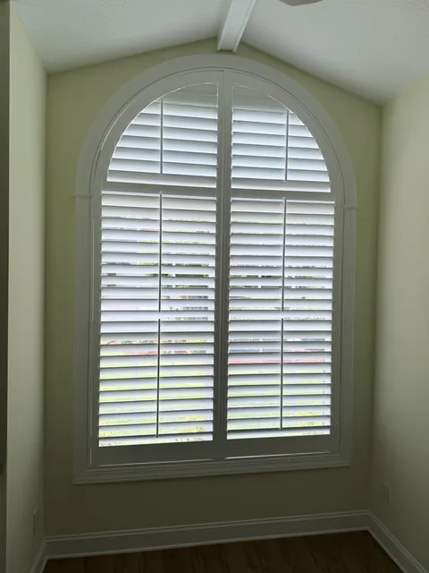 Center Open Arch Top Plantation Shutter in a yellow painted room