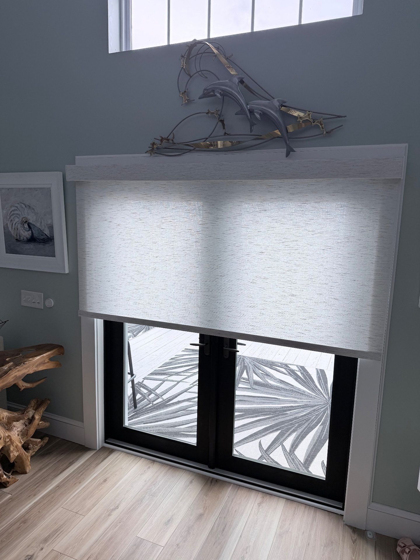White Roller Shade over a set of black french doors (Shown partially closed)