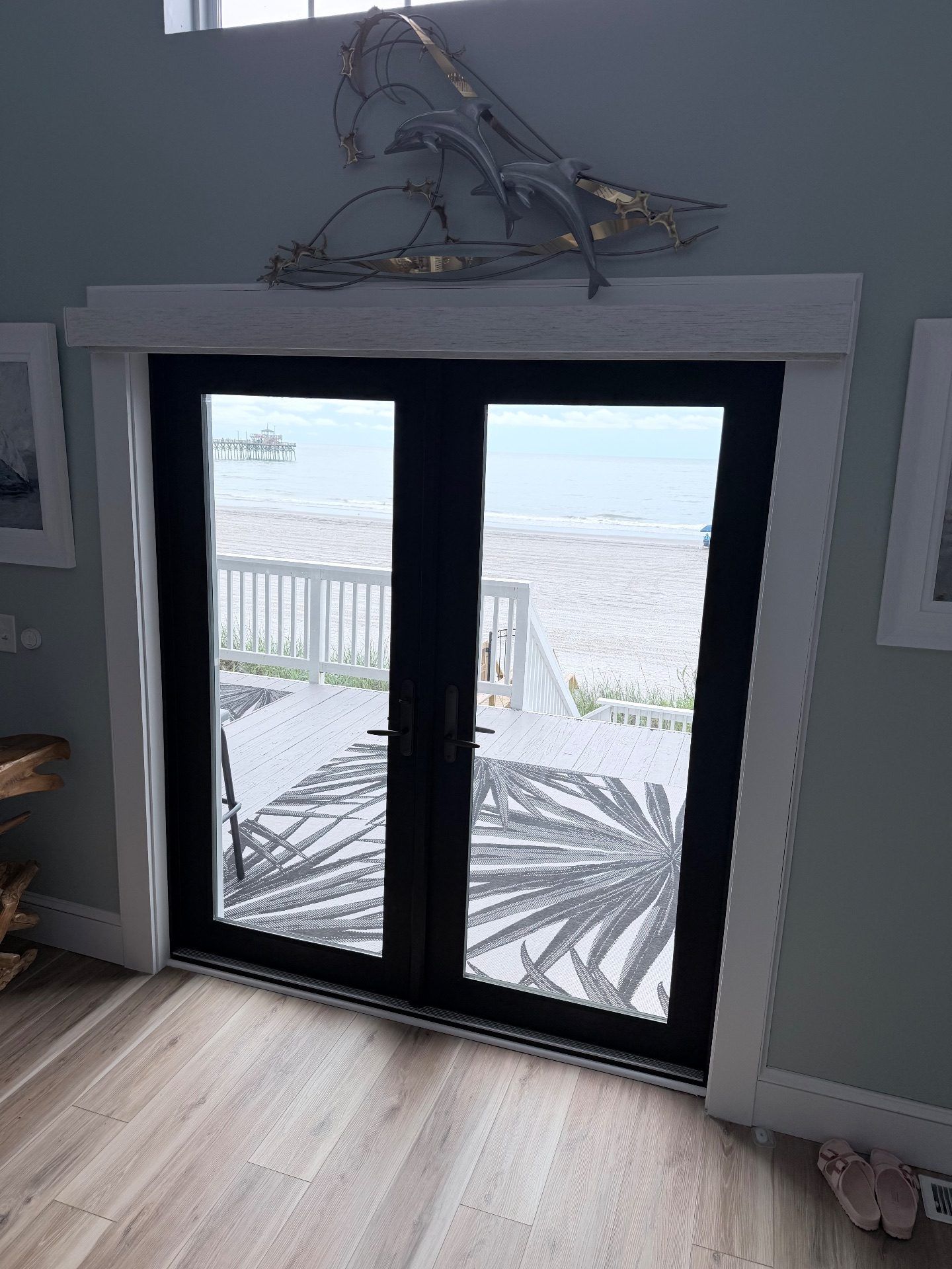 White Roller Shade over a set of black french doors (Shown open)