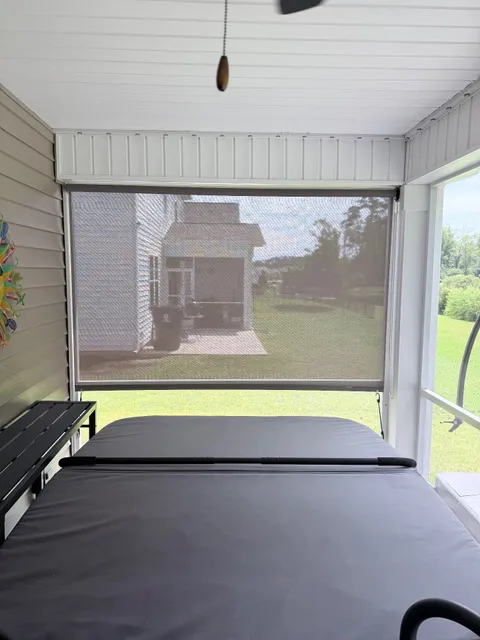 Outdoor roll-down Patio shade in sand color with bungee hold downs.