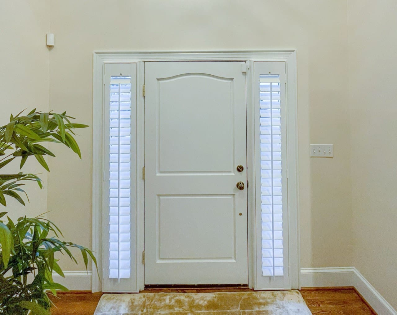 Narrow sidelite windows beside a front door fitted with plantation shutters